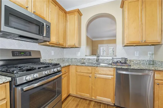 a kitchen with stainless steel appliances granite countertop a stove a sink and a microwave