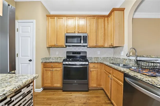 a kitchen with stainless steel appliances granite countertop a stove a sink and a microwave