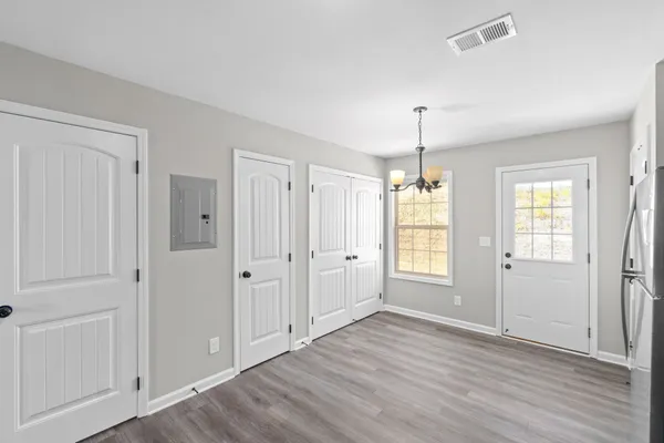 a view of an empty room with window and wooden floor