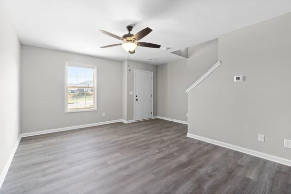 a view of an empty room with wooden floor and a window
