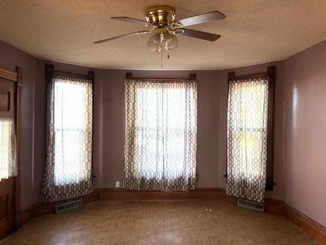 an empty room with a ceiling fan and windows