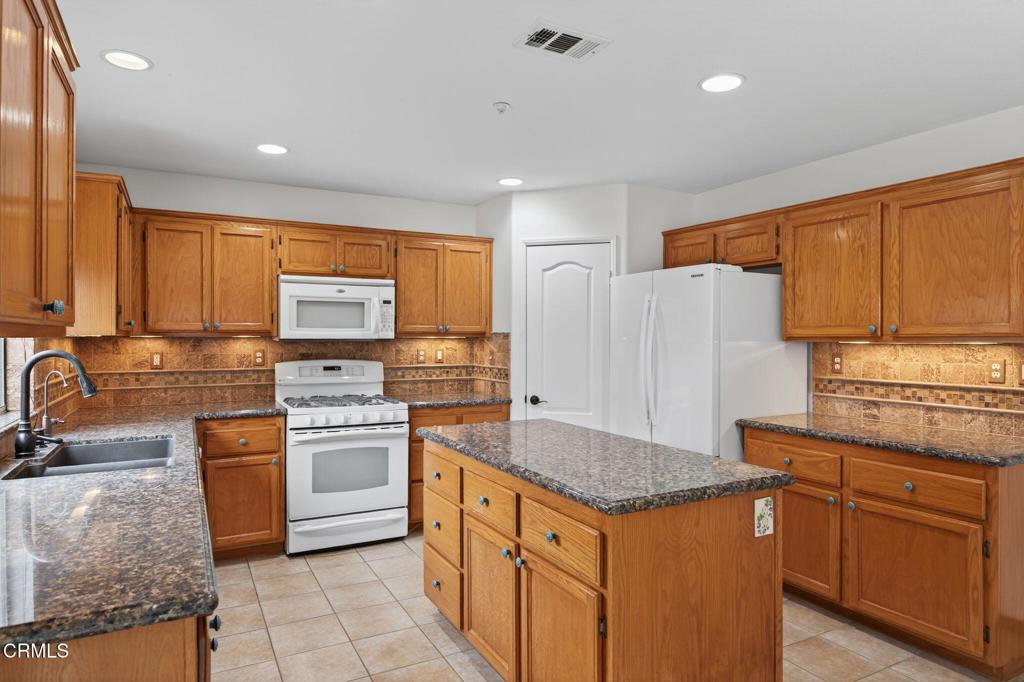 520 Festivo Street Oxnard, CA 93030 - Photo 11 of 31 a kitchen with stainless steel appliances granite countertop a stove a sink dishwasher a refrigerator and white cabinets with wooden floor