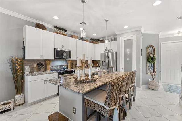 a kitchen with stainless steel appliances granite countertop a stove top oven a refrigerator a sink and a island