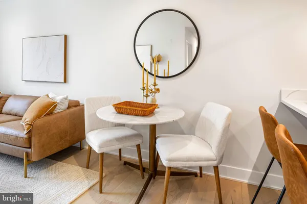 a living room with couches a mirror and a dining table with wooden floor