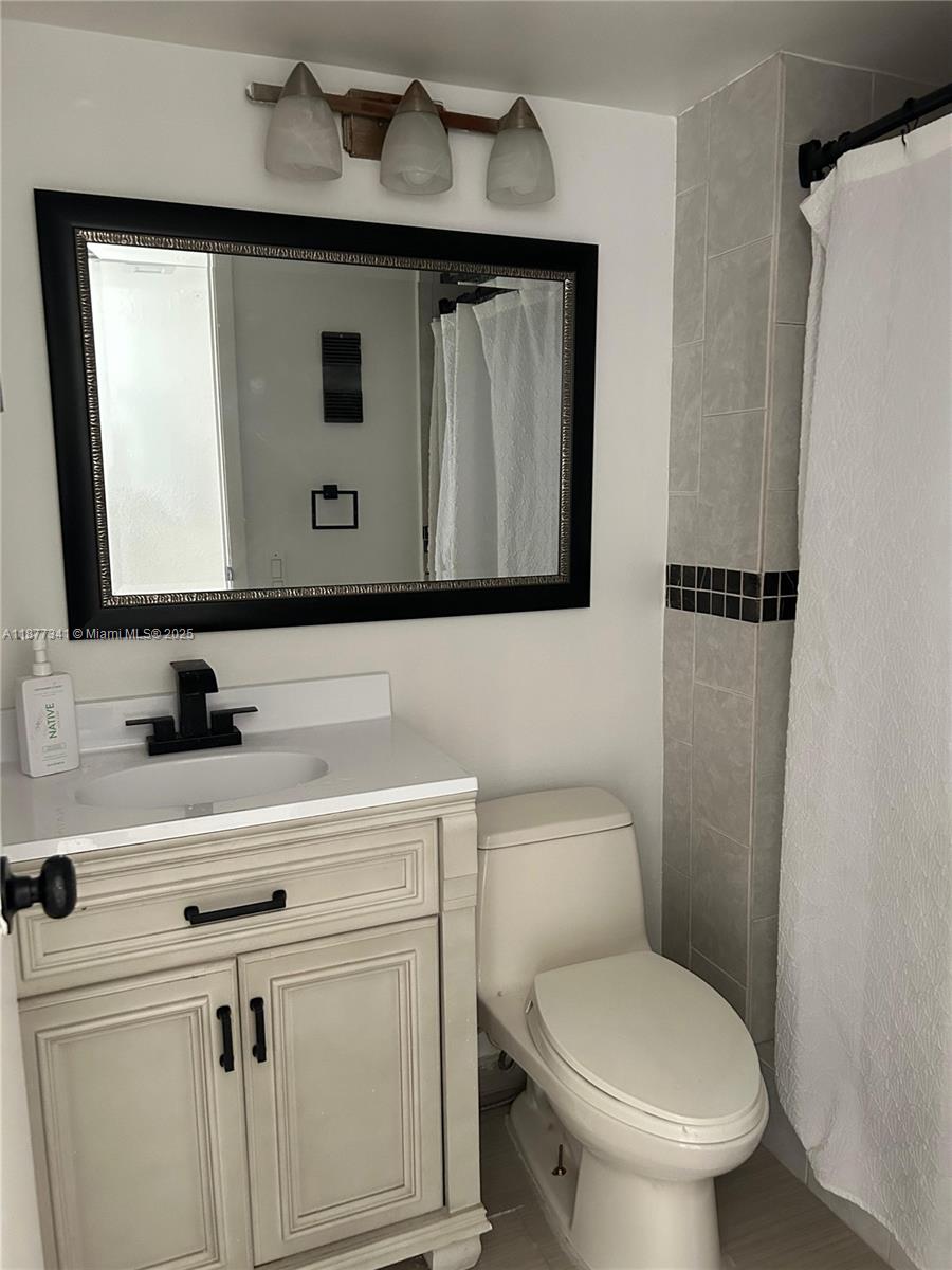 3100 West Rolling Hills Circle, Unit 702 Davie, FL 33328 - Photo 13 of 16 a bathroom with a toilet sink and mirror
