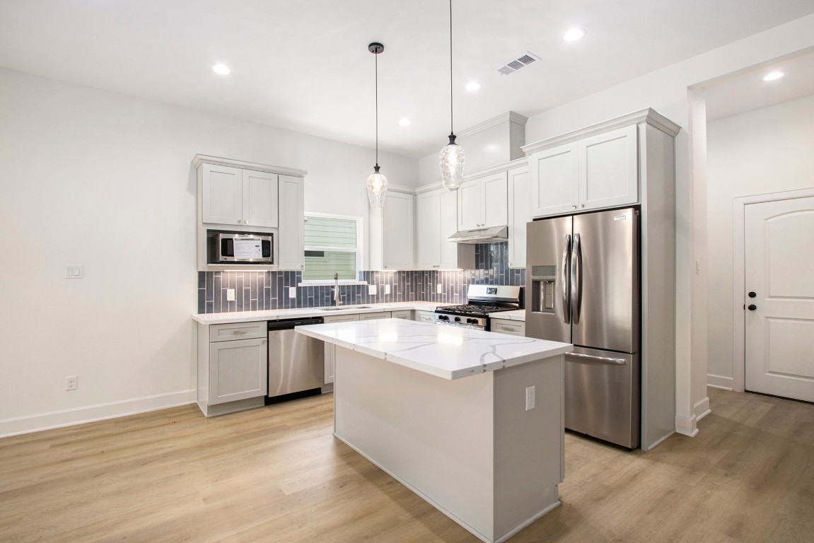 3810 Jackson Street Santa Fe, TX 77517 - Photo 7 of 29 a kitchen with stainless steel appliances granite countertop a refrigerator a sink dishwasher a stove and white cabinets with wooden floor