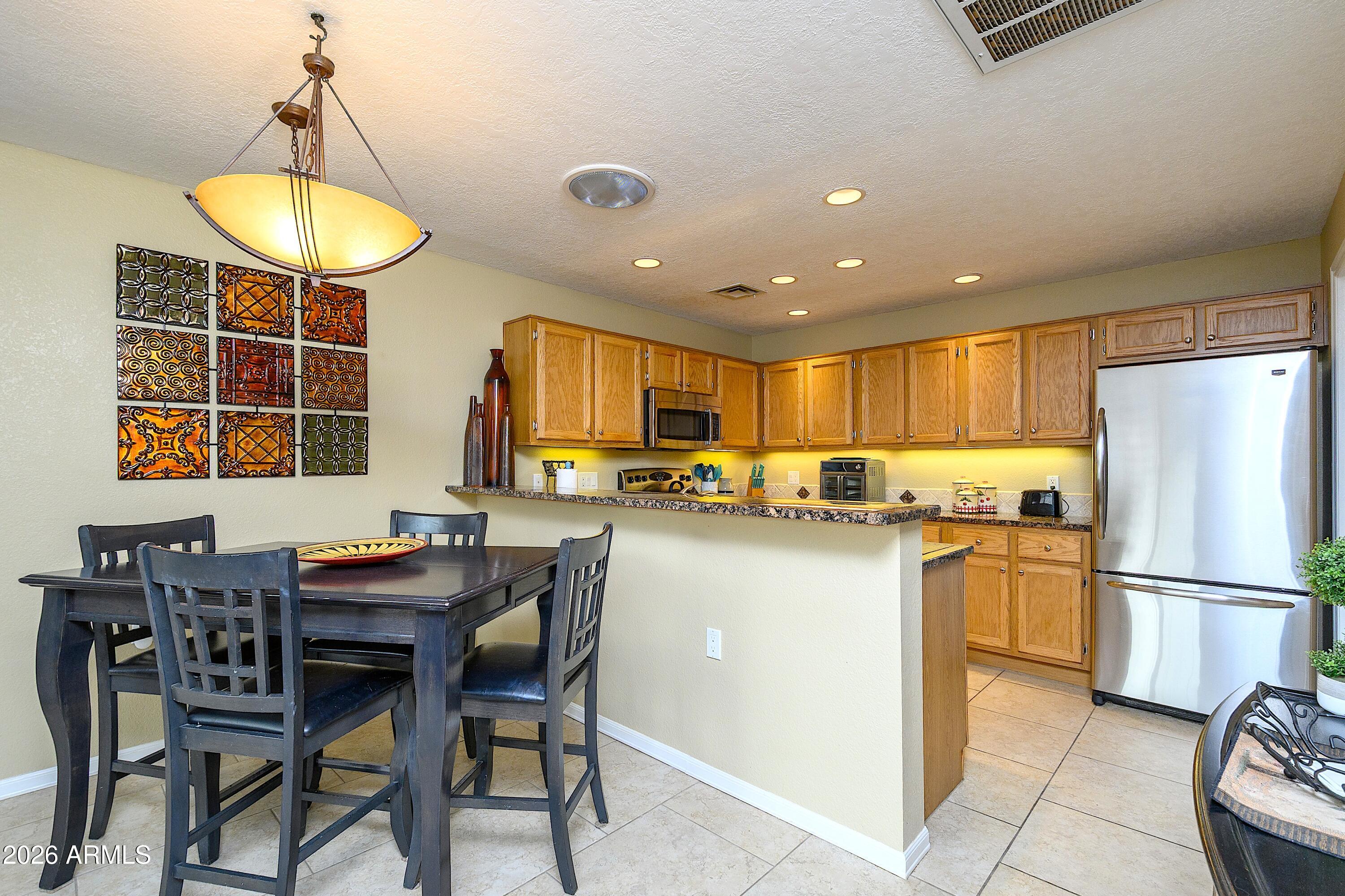 14300 West Bell Road, Unit 420 Surprise, AZ 85374 - Photo 9 of 27 a kitchen with a dining table chairs and refrigerator