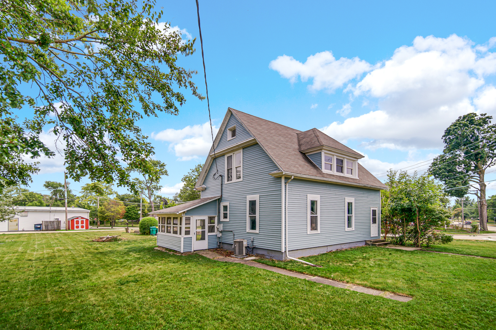 a view of a house with a big yard potted plants and large tree