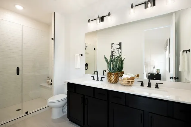 a bathroom with a double vanity sink toilet and shower