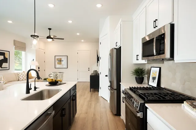 a kitchen with stainless steel appliances a sink a stove a refrigerator cabinets and a kitchen island