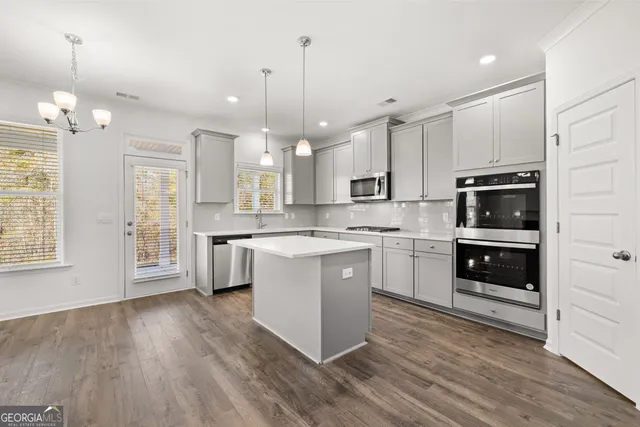 a large white kitchen with kitchen island a sink stainless steel appliances and white cabinets