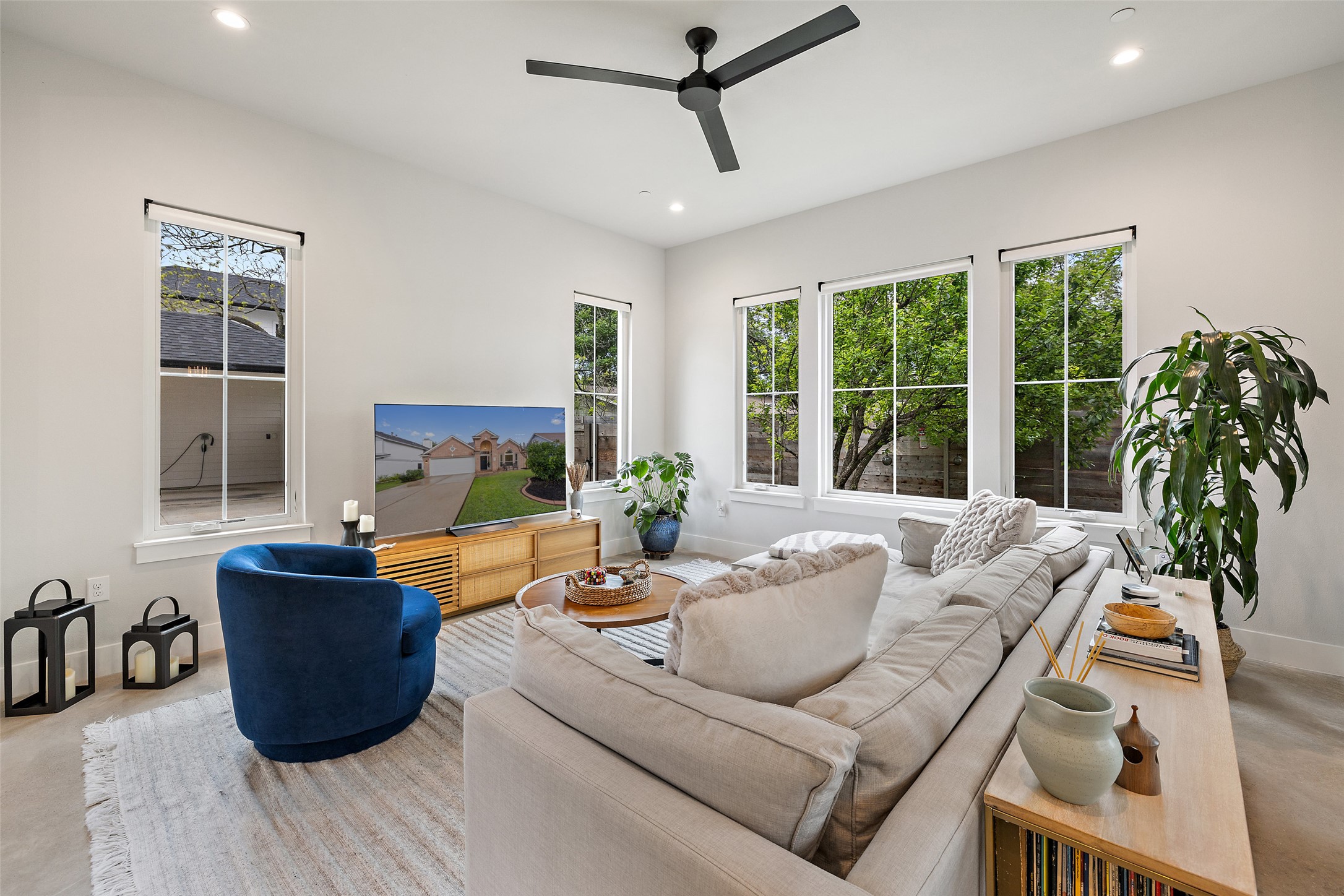 1504 Ruth Avenue, Unit 3 Austin, TX 78757 - Photo 4 of 39 A well-lit living space features high ceilings, a modern ceiling fan, and multiple windows overlooking greenery.