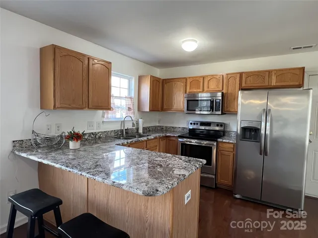 a kitchen with stainless steel appliances granite countertop a sink stove and refrigerator