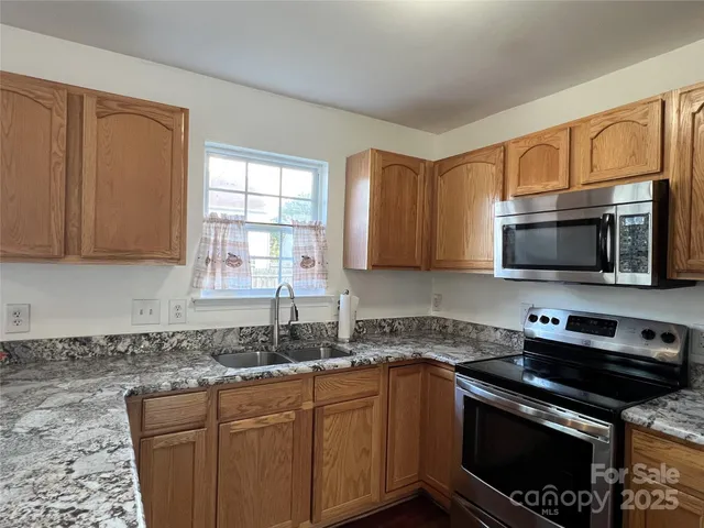 a kitchen with stainless steel appliances granite countertop white cabinets granite counter tops and a window