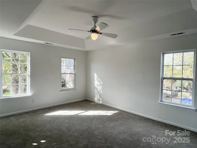 an empty room with windows and fan