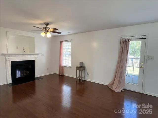 a view of empty room with a fireplace and wooden floor