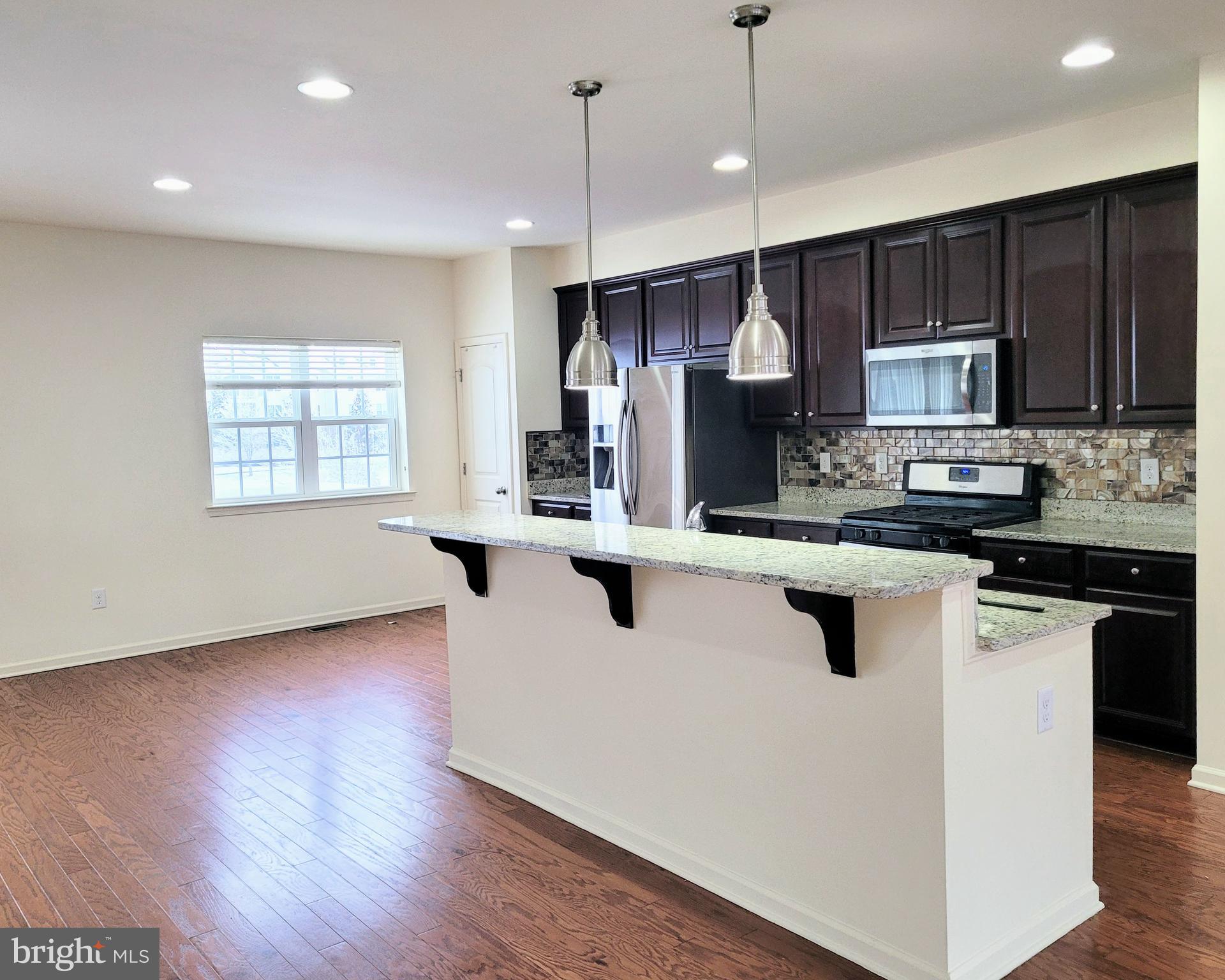 628 Rigel Way Bear, DE 19701 - Photo 5 of 20 a kitchen with stainless steel appliances granite countertop wooden cabinets a refrigerator a sink a stove a microwave and wooden floors