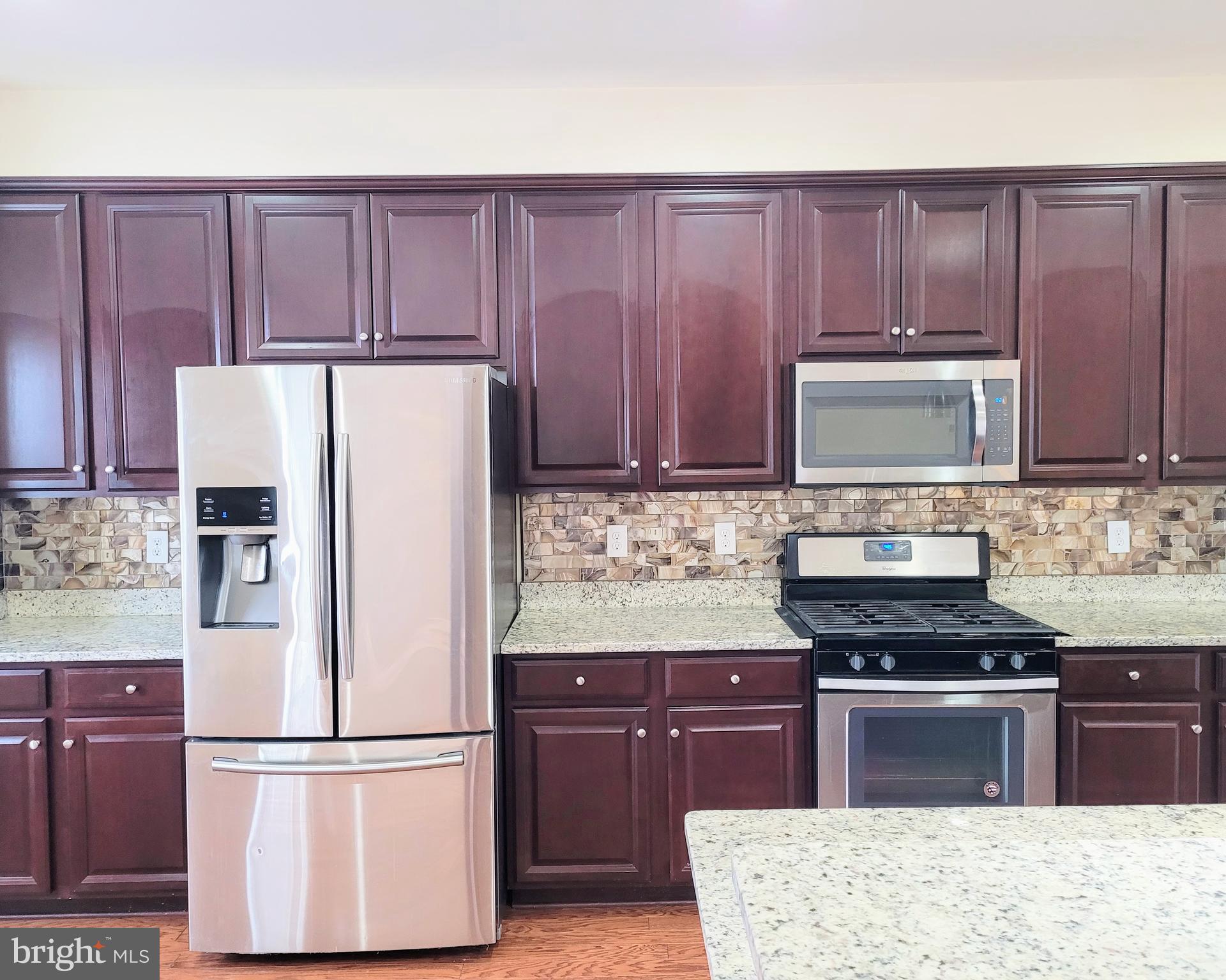 628 Rigel Way Bear, DE 19701 - Photo 7 of 20 a kitchen with granite countertop wooden cabinets and refrigerator