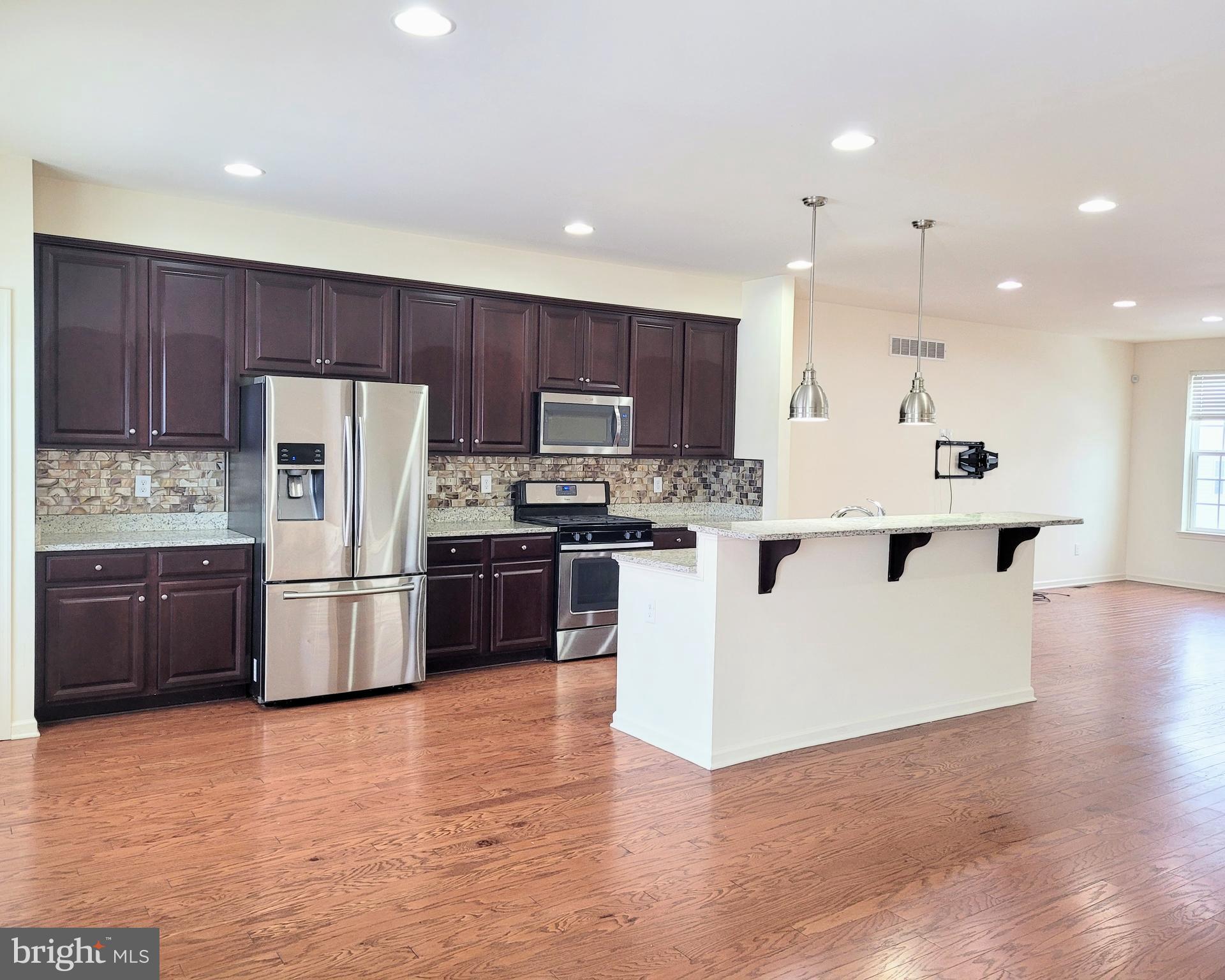628 Rigel Way Bear, DE 19701 - Photo 8 of 20 a large kitchen with stainless steel appliances kitchen island granite countertop a refrigerator stove a sink and a oven with wooden floor