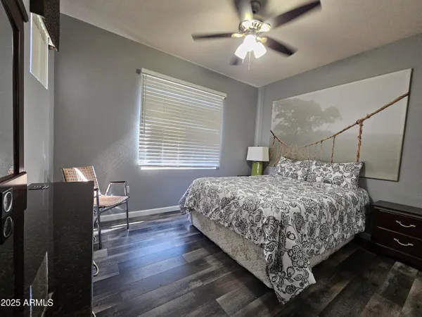 a bedroom with a bed and dresser with wooden floor