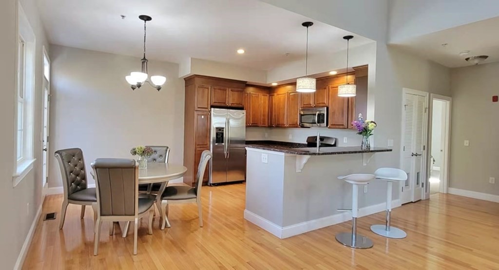 797 Highland Avenue, Unit 4 Needham, MA 02494 - Photo 6 of 21 a kitchen with stainless steel appliances kitchen island granite countertop a dining table chairs and granite counter tops