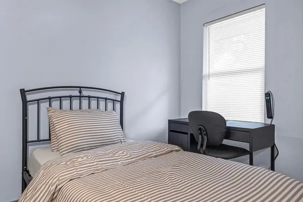 a bedroom with a bed a chair and a window