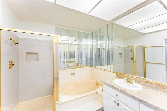 a bathroom with a granite countertop sink a mirror a bathtub and shower