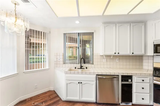 a kitchen with granite countertop a sink cabinets stainless steel appliances and a window