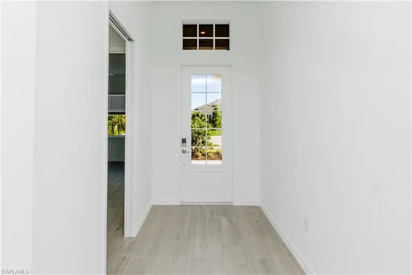 a view of a hallway with wooden floor and a bathroom