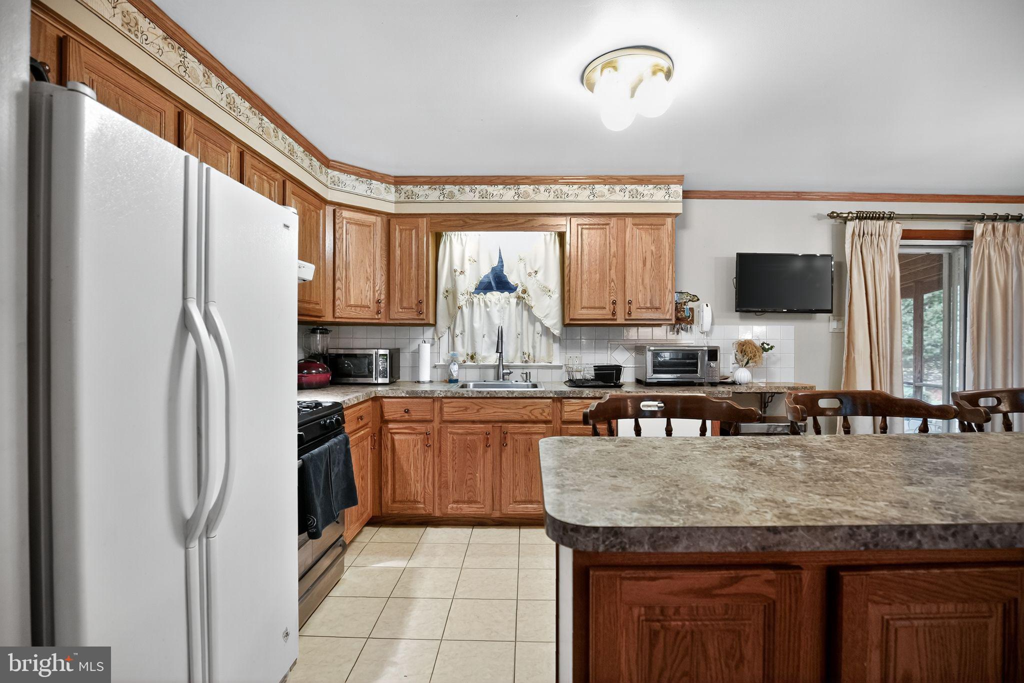 908 Pershing Road Blue Bell, PA 19422 - Photo 13 of 24 a kitchen with granite countertop a refrigerator a stove a sink a dining table and chairs