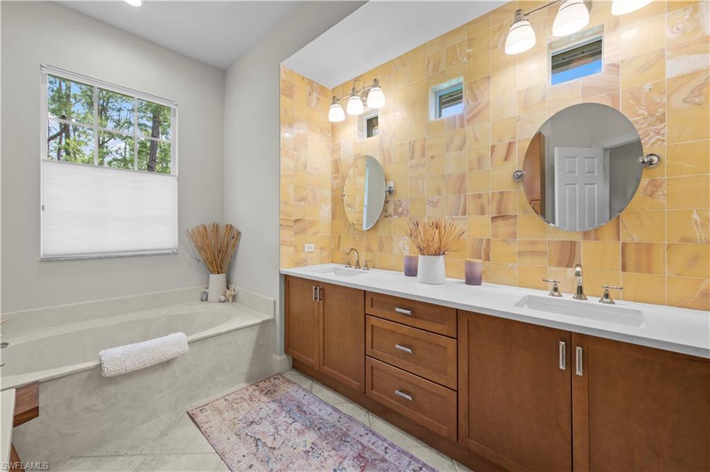22043 Sycamore Grove Estero, FL 34135 - Photo 30 of 44 a spacious bathroom with a double vanity sink a mirror a bathtub and next to a window