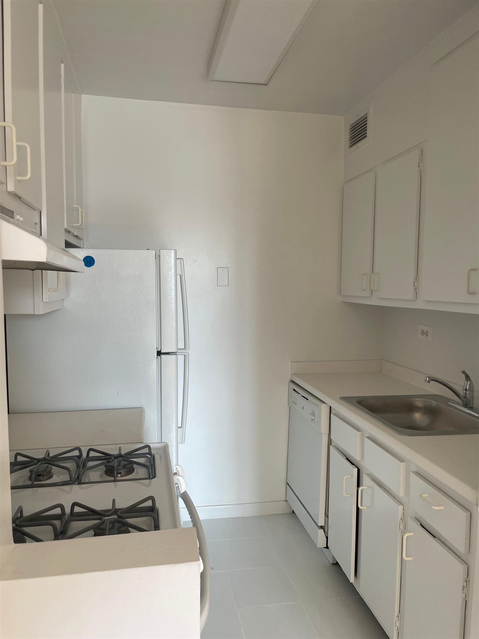 200 East 72nd Street, Unit 22D Manhattan, NY 10021 - Photo 5 of 10 a white kitchen with sink stove and refrigerator