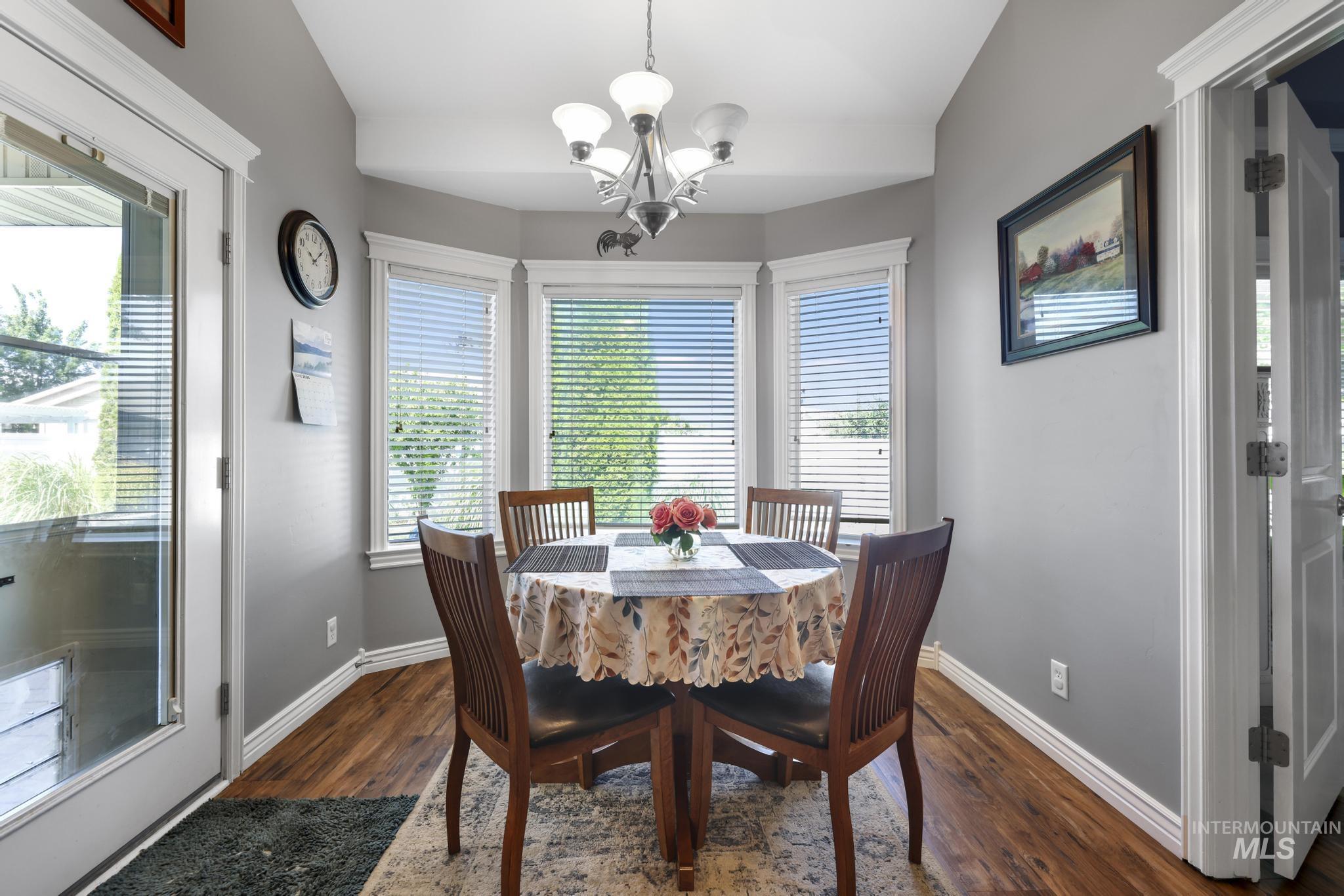 467 Wildrose Loop Twin Falls, ID 83301 - Photo 13 of 46 Dining area with bay windows, wood-finish flooring, a contemporary chandelier, and a white trim package
