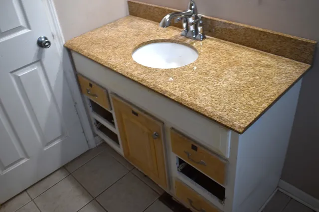 a bathroom with a granite countertop sink and a mirror