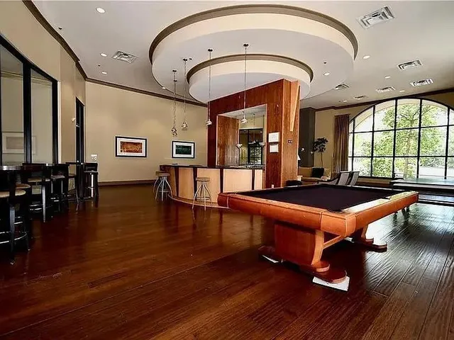 a room with furniture pool table wooden floor and windows