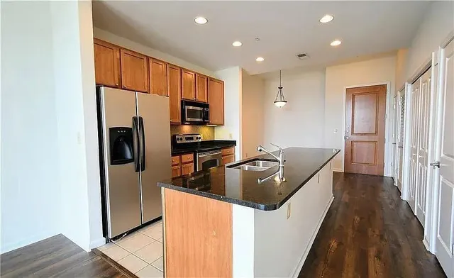 a kitchen with stainless steel appliances granite countertop a refrigerator a stove and a sink with wooden floor
