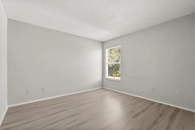 an empty room with wooden floor and window
