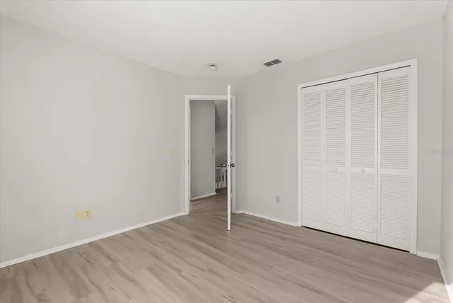 a view of an empty room with wooden floor and closet