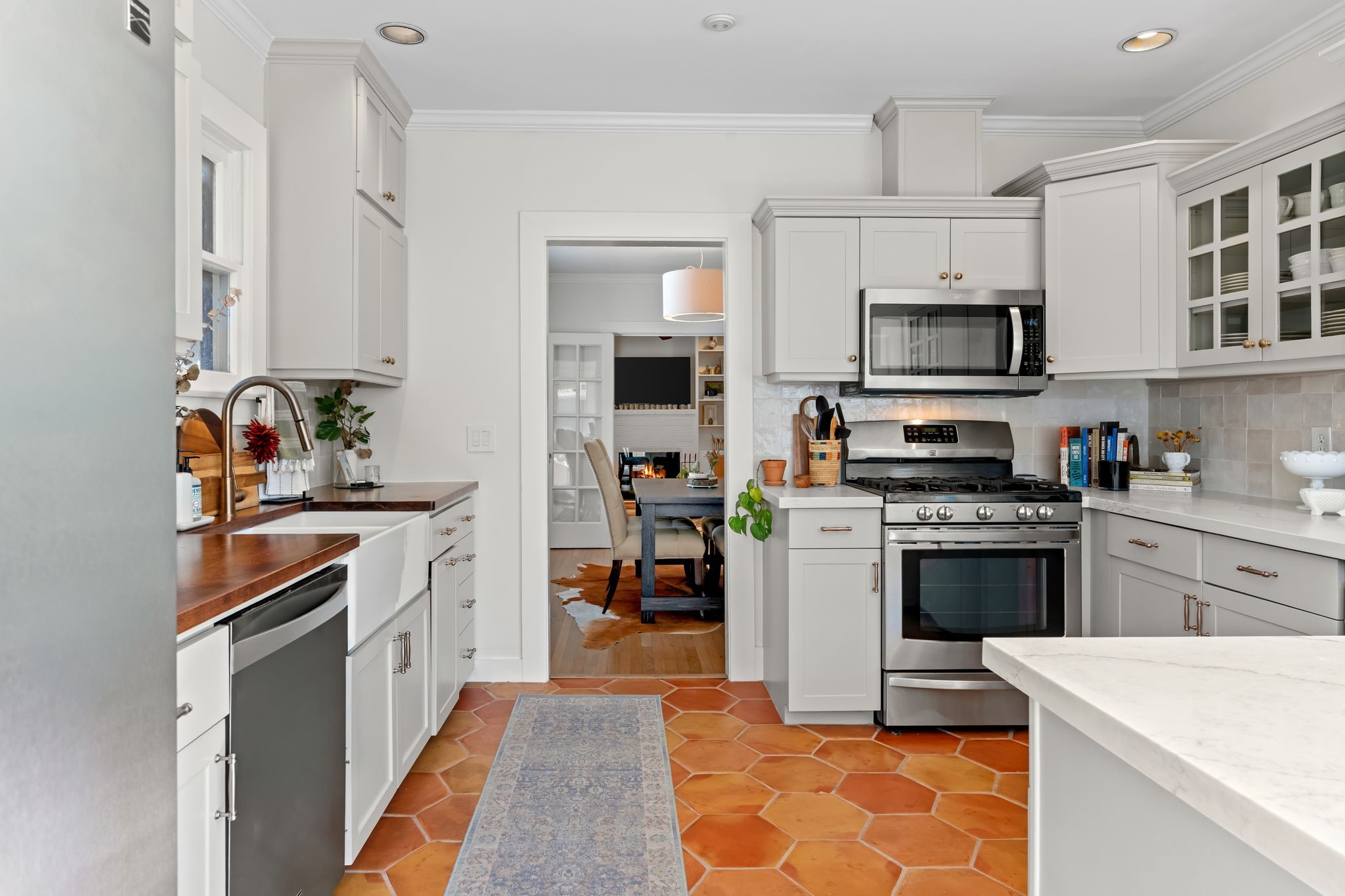1002 West Cottage Street Houston, TX 77009 - Photo 11 of 37 This reverse angle shows the gas range, built-in microwave, dishwasher, and stainless steel appliances that come with the home. The doorway connects straight to the dining room, keeping the cook within reach of the rest of the house. Butcher block counters on the sink side and granite on the island give the kitchen both warmth and durability.