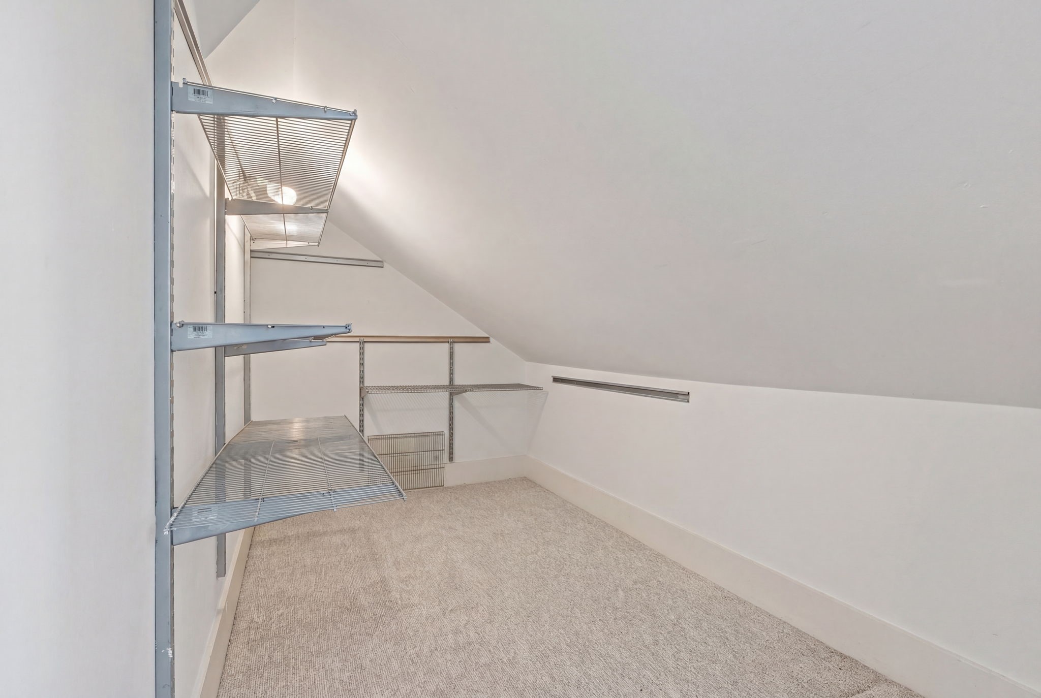 1002 West Cottage Street Houston, TX 77009 - Photo 22 of 37 Spacious upstairs closet with built-in shelving provides excellent storage and organization options. Sloped ceiling design adds character while maximizing usable space. Ideal for clothing, seasonal storage, or additional organization needs.