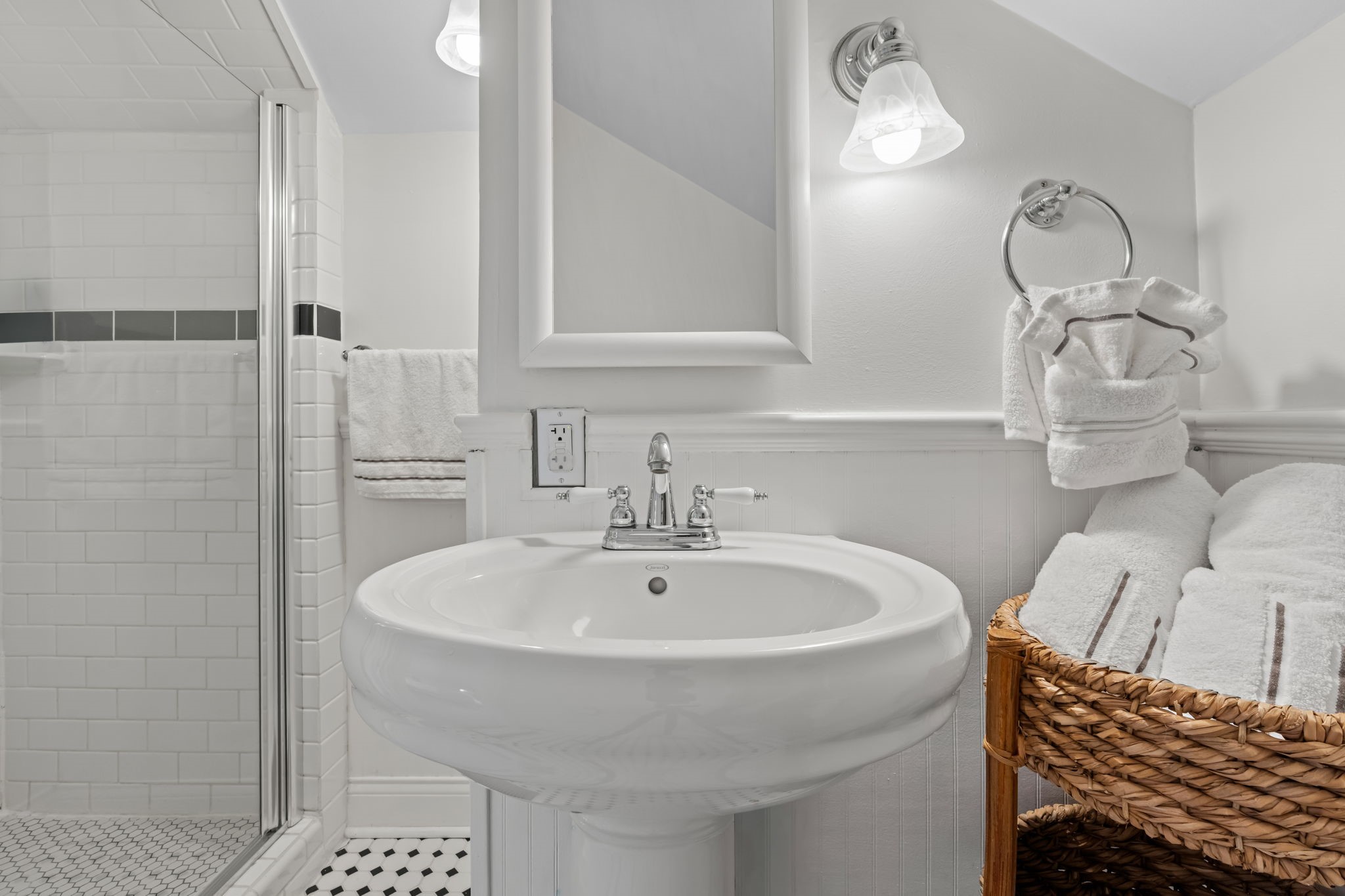 1002 West Cottage Street Houston, TX 77009 - Photo 23 of 37 The second full bath is located upstairs and exclusively serves the third bedroom, featuring a pedestal sink, walk-in shower with subway tile surround, and mosaic tile flooring. Beadboard wainscoting and chrome fixtures keep the look clean and classic. Having a dedicated bath on this level reinforces the suite-like independence of the upstairs living space.