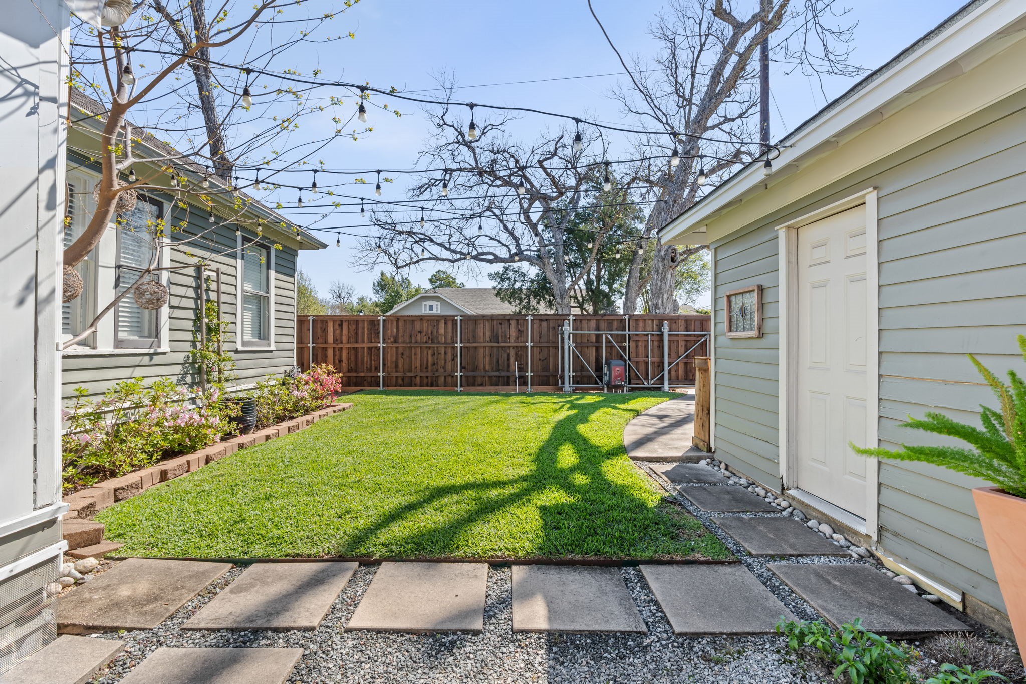 1002 West Cottage Street Houston, TX 77009 - Photo 25 of 37 The fenced backyard features a well-maintained lawn, string lights, landscaped flower beds, and a paver walkway leading to the oversized detached garage. A sprinkler system is in place, and landscaping maintenance is included in the lease one less thing to manage. The gate at the back provides access to the garage and driveway from the yard.