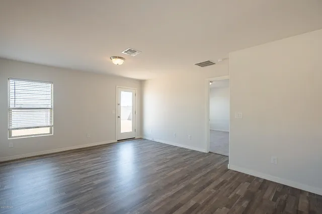 an empty room with wooden floor and window