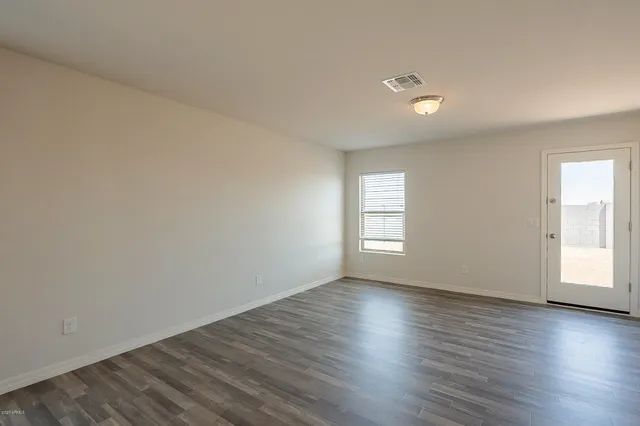 a view of an empty room with wooden floor and window