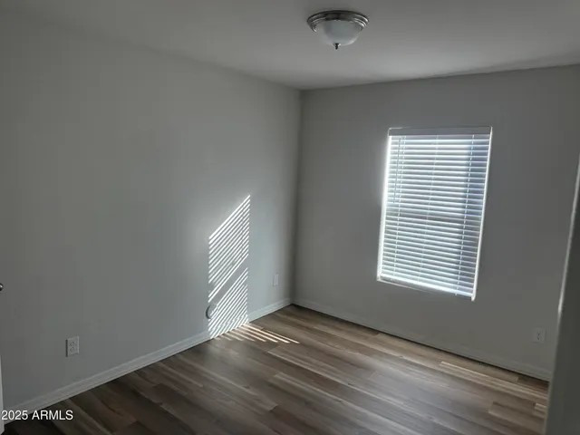 an empty room with wooden floor cabinet and windows