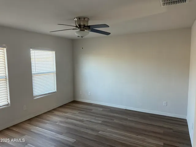 an empty room with wooden floor fan and windows