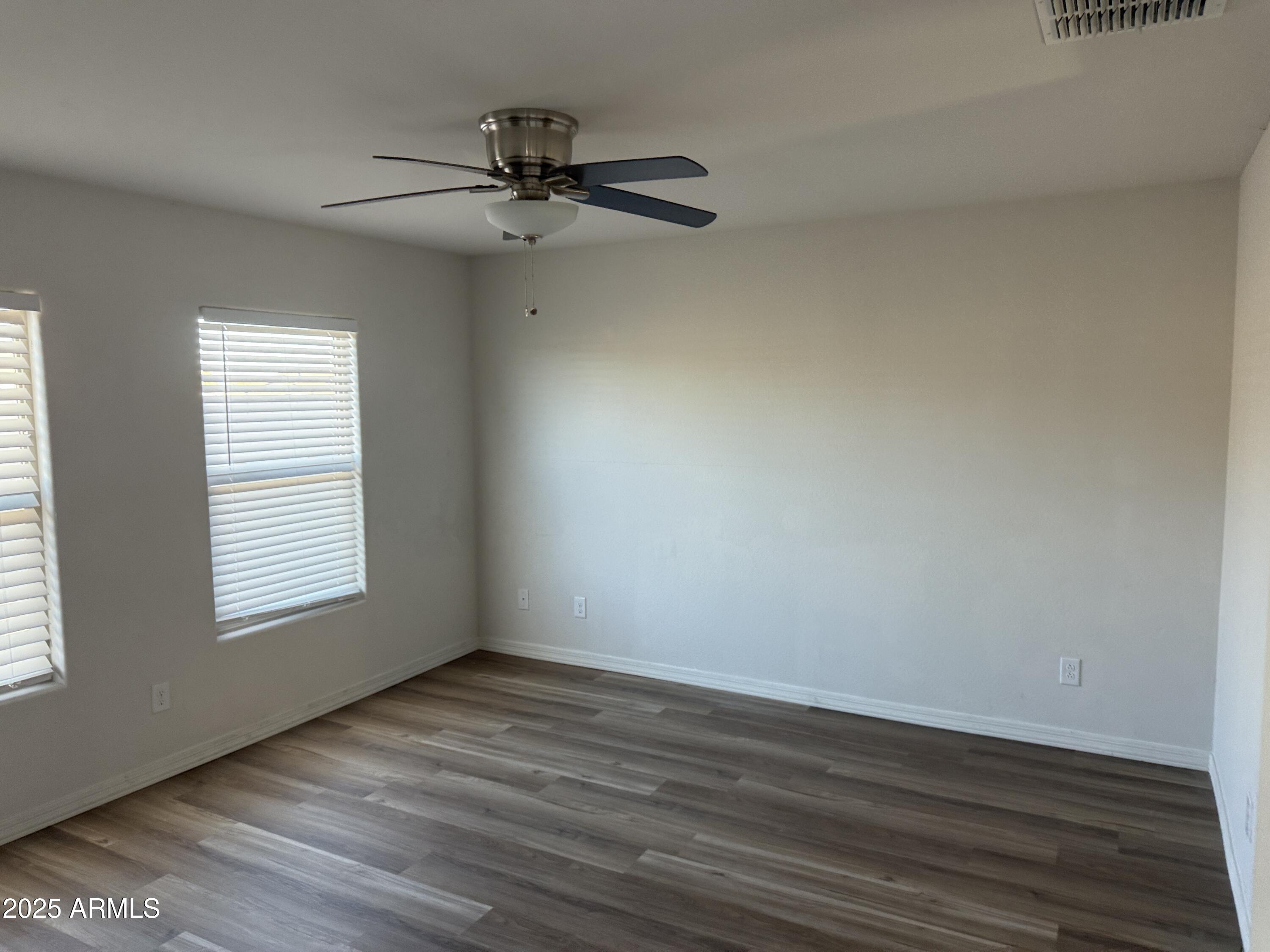 944 Starview Avenue Coolidge, AZ 85128 - Photo 18 of 36 an empty room with wooden floor fan and windows