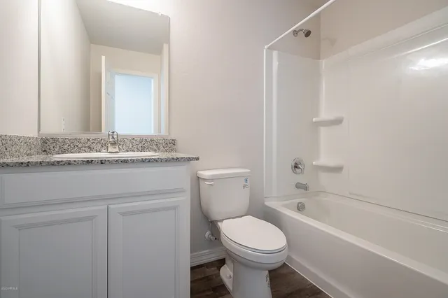 a bathroom with a granite countertop toilet sink and mirror