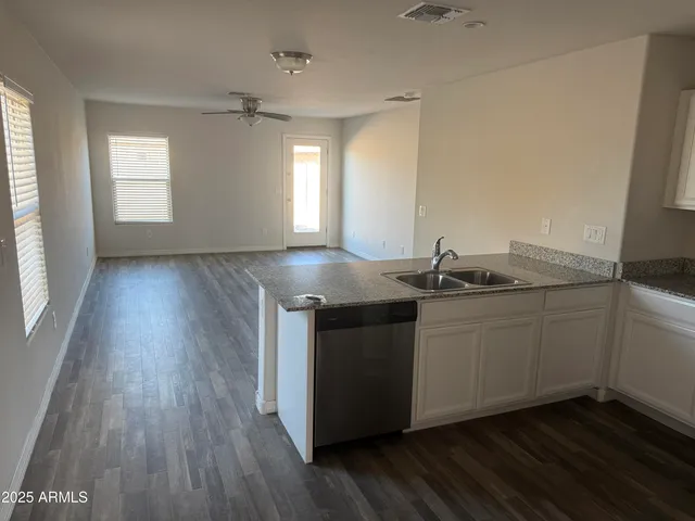 a kitchen with granite countertop a sink and wooden floors