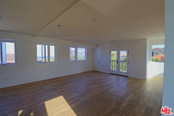 a view of an empty room with a window and wooden floor